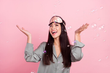Photo of excited charming woman nightwear mask smiling throwing water bubbles rising arms isolated...