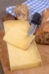 Morceaux de fromage de Laguiole avec un couteau sur une planche à découper à côté d'un morceau de pain en gros plan