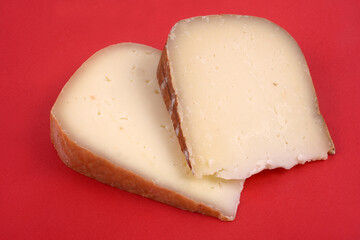 Morceau d'Ossau Iraty et morceau de fromage de brebis en gros plan sur fond rouge