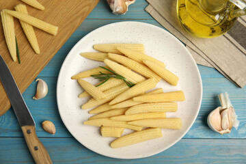 Fresh baby corn cobs on blue wooden table, flat lay