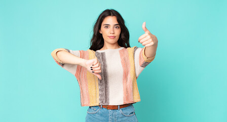 young pretty woman feeling confused, clueless and unsure, weighting the good and bad in different...