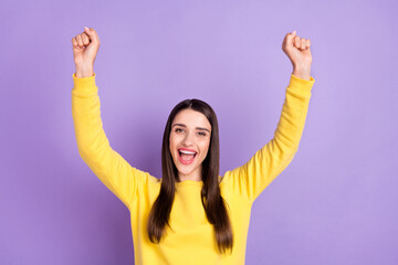 Photo of cheerful positive young woman raise fists good mood winner smile isolated on purple color background