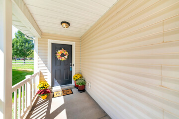 Front door porch with decorative displays of flower wreath and potted flowers at the floor