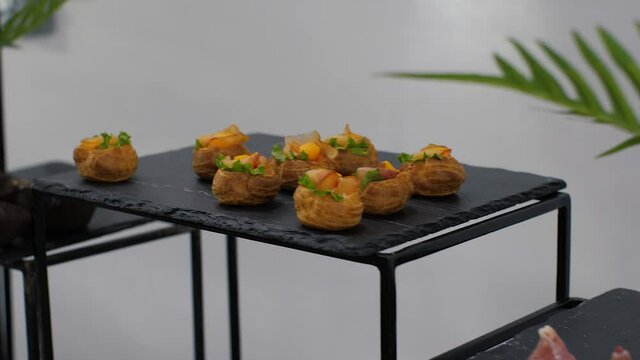 Camera pans along the delicious snacks for guests on a black table decorated with palm leaves