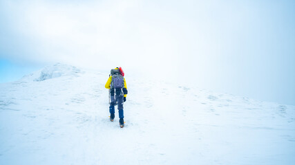 Fototapeta na wymiar Lonely tourist trekking winter mountain top covered with snow