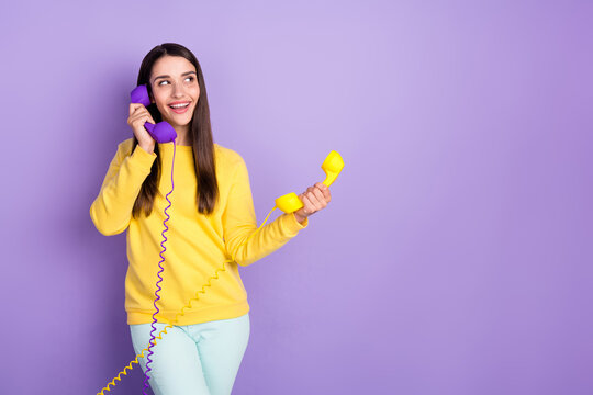 Photo of pretty young charming woman look empty space smile hold phone wire isolated on violet color background