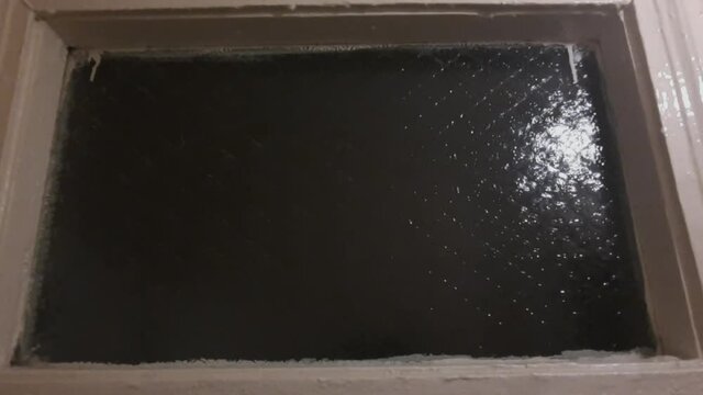 A female hand arm silhouette appears through glass and slowly goes back. 
