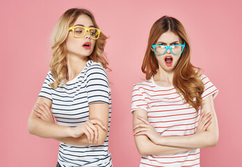 two girlfriends striped t-shirts with sunglasses pink background