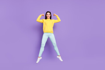 Fototapeta na wymiar Full length body size view of attractive cheerful girl jumping showing strong muscles isolated over violet purple color background