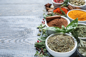 Fototapeta na wymiar Different natural spices and herbs on grey wooden table. Space for text