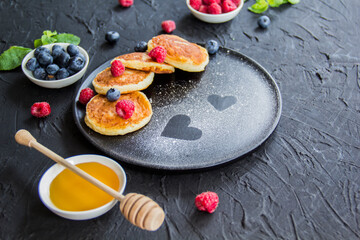 A healthy breakfast of cheese pancakes, berries, and honey. Creative atmospheric decoration