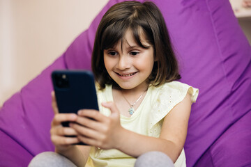 Kid Playing Smartphone. Mobile technology concept. Portrait teenager girl holding smart phone. Child Browsing Internet on Phone, Teenager Girl Reading Messages, Searching Online on Devices