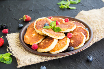A healthy breakfast of cheese pancakes, berries, and honey. Creative atmospheric decoration