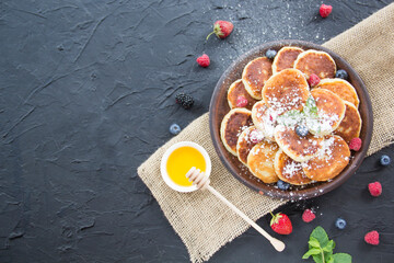 A healthy breakfast of cheese pancakes, berries, and honey. Creative atmospheric decoration