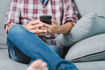 Close-up shot of a businessman in casual wear looking at the business report on document and smartphone while sitting on the couch in relaxed posture in the home office. Business stock photo