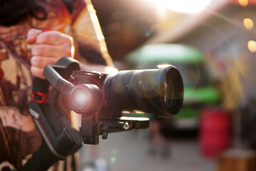 A man with a camera and a lens. Photocamera on the stabilizer for video shooting. Blurred background and sun glare