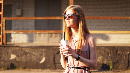 Young woman with a cup of lemonade outside. Sunny day on urban food court.