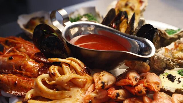 Cooked mixed seafood, lobster shrimp, king prawns, mussels, oysters and squids are served on a salver large plate for luxury restaurant visitors. Traditional meditarian dish rotating on a tray.