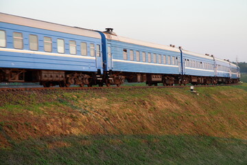 Obraz premium Old blue passenger train motion bottom up side view at sunny summer evening