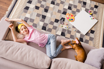 Top above high angle view portrait of attractive cheery preteen girl resting with doggy on cozy divan sleeping at home house flat indoors