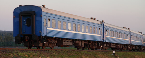 Old blue passenger train last wagon at sunny summer evening