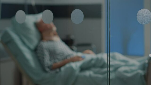 Sick old man laying in hospital ward bed with cervical neck collar at medical facility. Elder patient sitting in intensive care room waiting for surgery diagnosis from doctor to start treatment