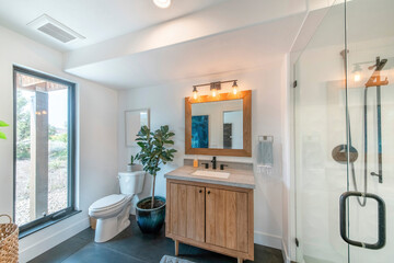 Boho bathroom design with large window near the toilet bowl with plants on top and side