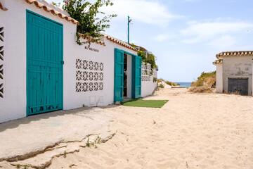 
Chalet de playa con puerta de entrada de madera pintada de color verde y muro de color blanco