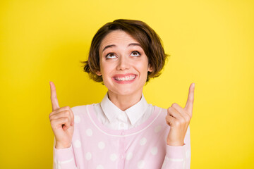 Photo portrait cheerful girl smiling pointing up fingers copyspace promoting isolated vivid yellow color background