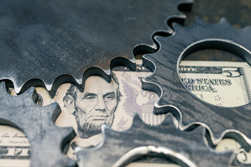 portrait of the president with a five dollar bill next to the gears