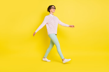 Full length body size photo of cheerful model stepping looking empty space isolated vibrant yellow color background