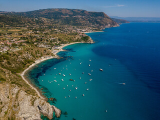Obraz premium Aerial view of moored boats floating on a transparent sea. Scuba diving and summer holidays. Capo Vaticano, Calabria, Italy. Promontory. 