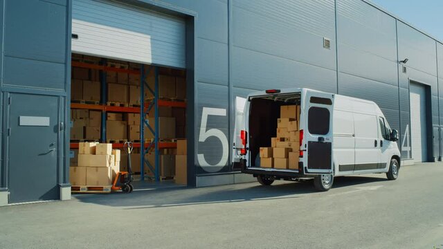 Outside of Logistics Warehouse with Open Door, Delivery Van Loaded with Cardboard Boxes. Truck Delivering Online Orders, Purchases, E-Commerce Goods, Wholesale Merchandise. Establishing Wide Shot
