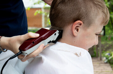 boy haircut with clipper in countryside