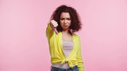 upset young woman showing thumb down isolated on pink