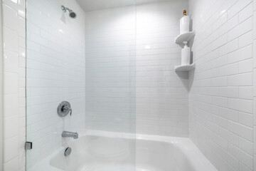Alcove bathtub with glass wall divider and a wall with white tiles - obrazy, fototapety, plakaty