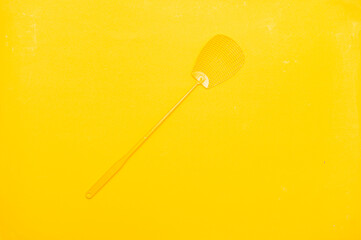Yellow fly swatter isolated on yellow background