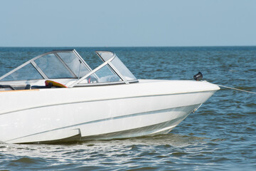 A white speedboat or motor boat sailing in the blue sea.