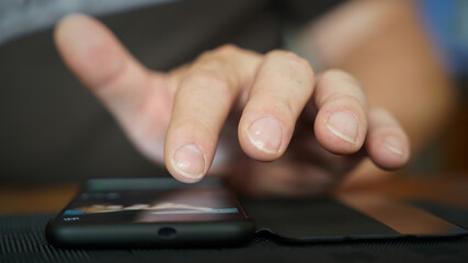 Fingers of a person operate a smartphone lying on the table 