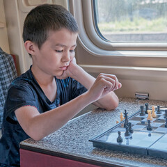 Fototapeta na wymiar Asian young boy playing chess at train.