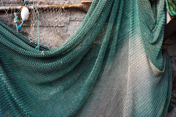 Fishing net hanging on a wall for drying. - obrazy, fototapety, plakaty