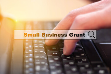 Small Business Grant - a man writes on a laptop keyboard. Small business investment search and support concept