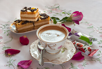 Cup of coffee on a saucer with candy and cake