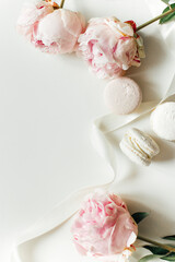 top view of beautiful pink peonies and macaroons on light background