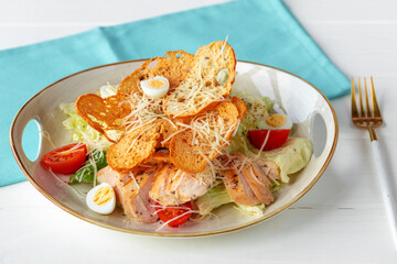 Caesar salad with grilled chicken on white wooden background