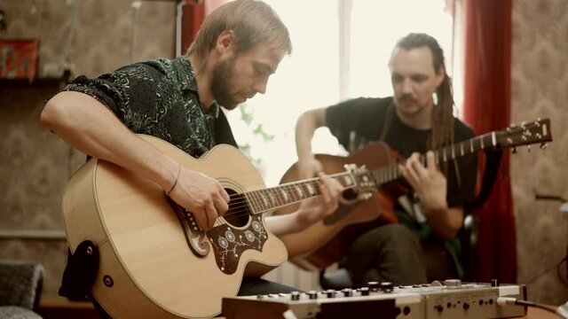 Adult men playing guitars at home