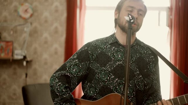 Male guitarist singing song at home