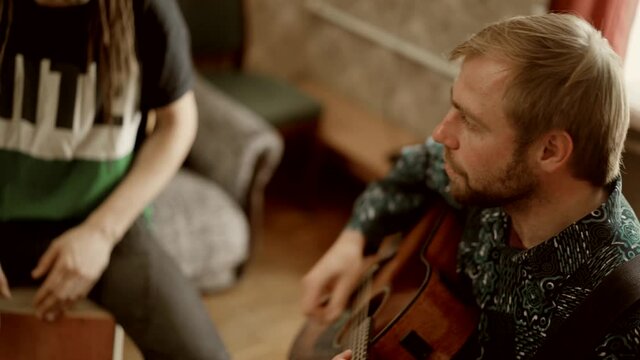 Male musician playing guitar and singing with frie