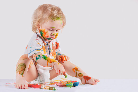 A child sitting chaotic painted his face and clothes with paint. Children's antics.