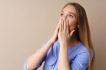 Shocked young woman looking up and .covers her mouth with hands